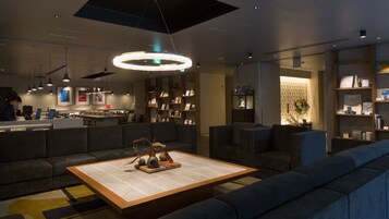 A modern lobby with a reception desk, seating areas, and a decorative centerpiece on a coffee table.