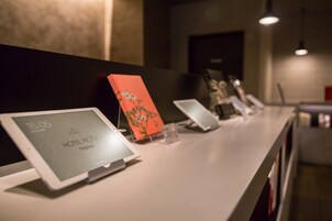 Un mostrador de recepción de hotel con varias tabletas que muestran la hora y el nombre del hotel.
