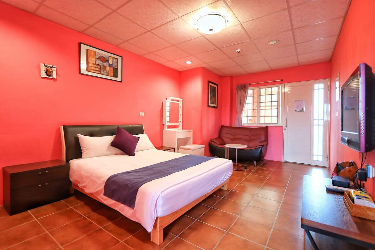 A room with a bed, a chair, a small table, and a television.