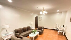 A modern living room with a sofa, armchairs, a coffee table, and a dining area with chairs. - Crown Royale Hotel (Balanga)