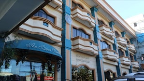 A multi-story hotel with a curved facade, balconies, and a sign reading "The Silver Room." - Crown Royale Hotel (Balanga)