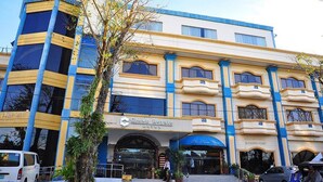A hotel with a prominent entrance, a sign for 'Crown Royale Hotel', and a blue awning over the entrance. - Crown Royale Hotel (Balanga)