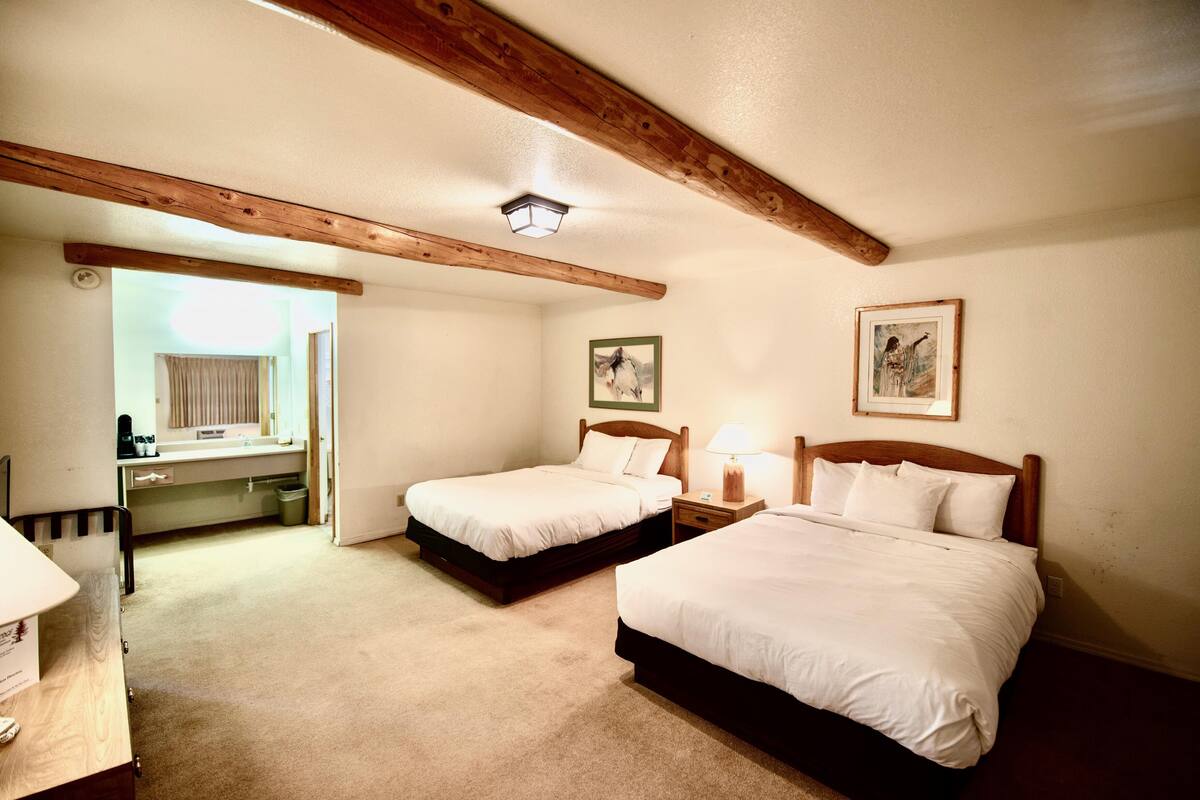 A bedroom with two beds, a desk, and a chair.