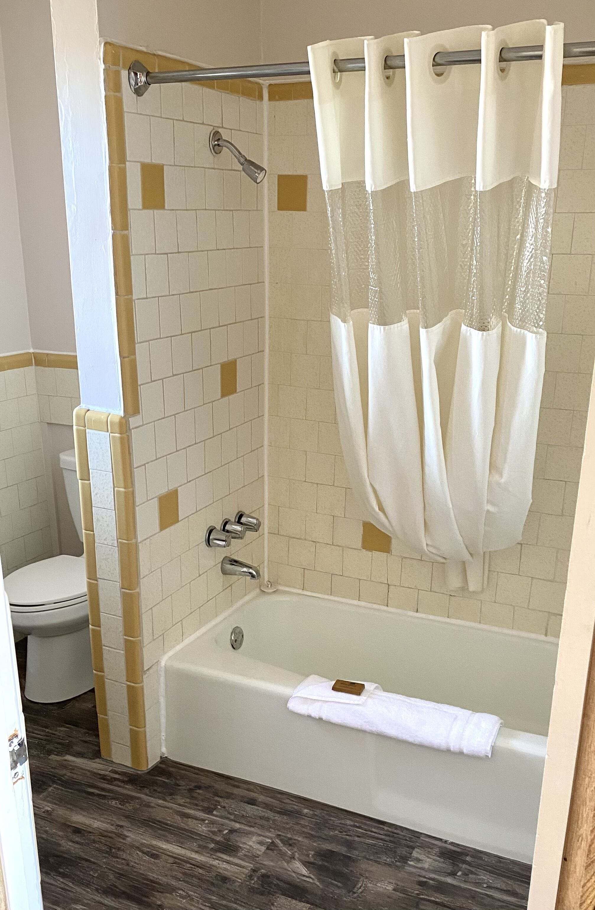 Een badkamer met een badkuip, douchegordijn en betegelde wanden.
