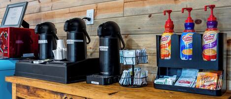 A coffee station with a coffee maker, hot water dispenser, and various coffee pods.
