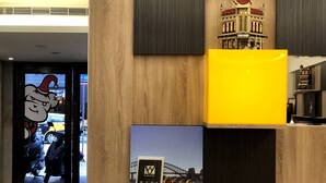 A hotel reception area with a wooden reception desk, a model of a building, and a Sydney Harbour bridge backdrop. - Fairytale YiSu Hot Spring Hotel (Jiaoxi)