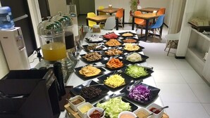 A buffet table with various dishes and condiments, including salad, rice, and sauces, in a dining area with chairs and tables. - Fairytale YiSu Hot Spring Hotel (Jiaoxi)
