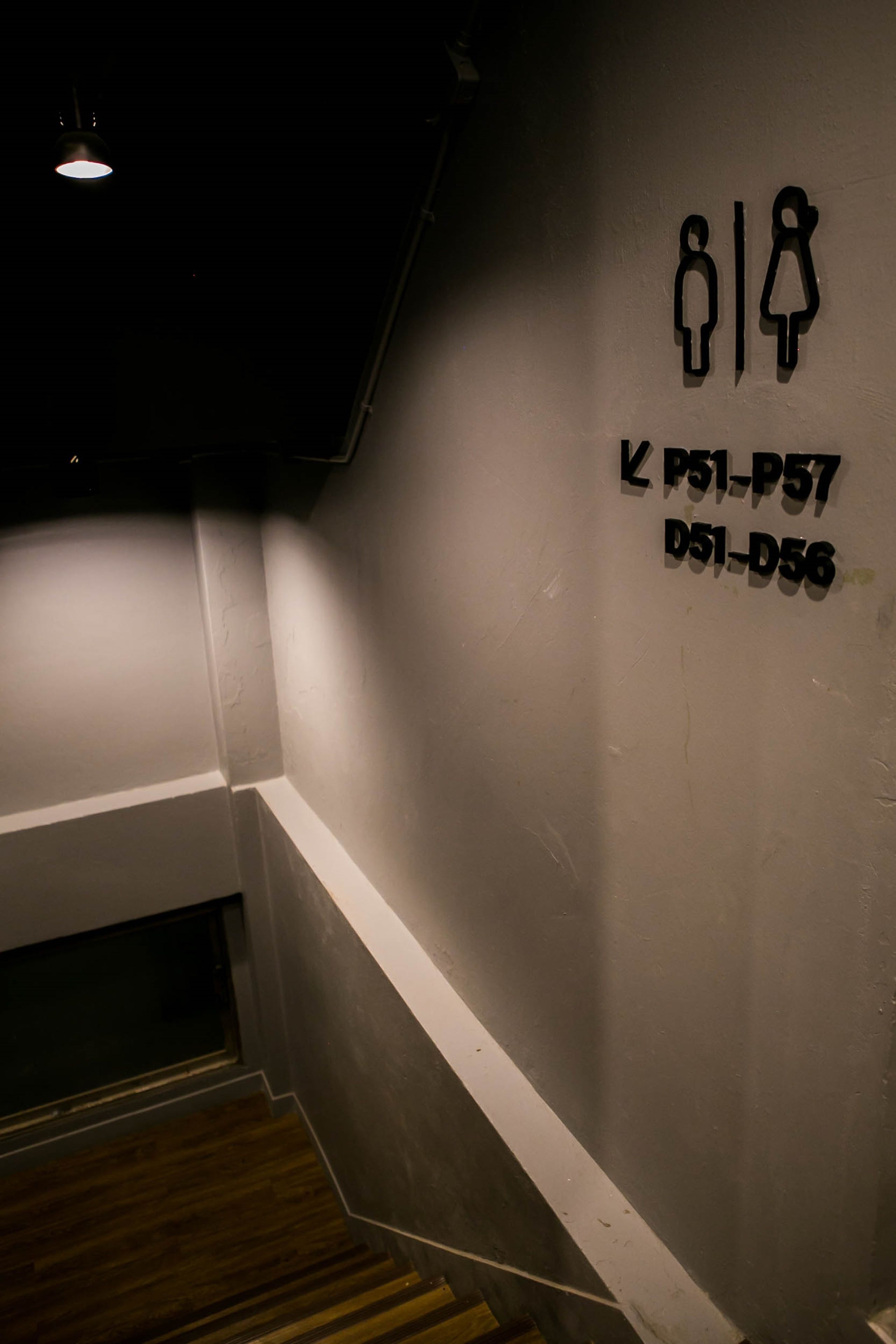 A corridor with a wall-mounted sign indicating restrooms and a staircase.