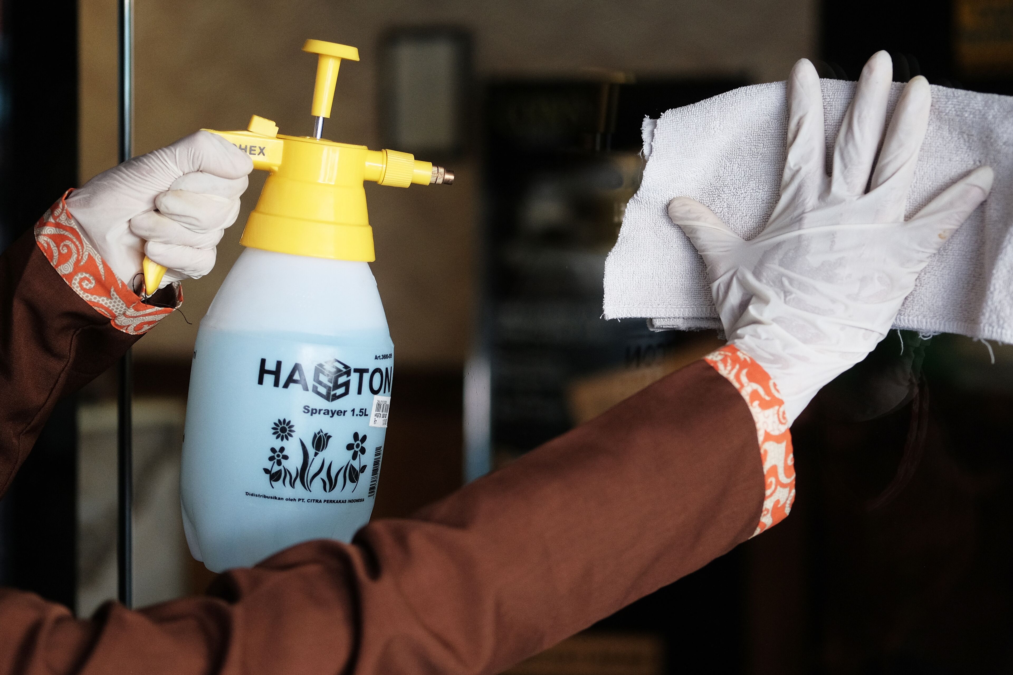 A person cleaning a window with a spray bottle and a cloth.