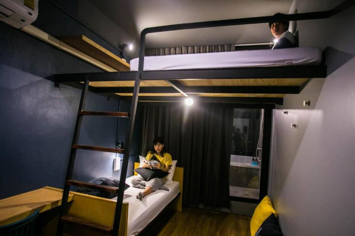 A bunk bed room with a ladder, a small table, and a refrigerator.