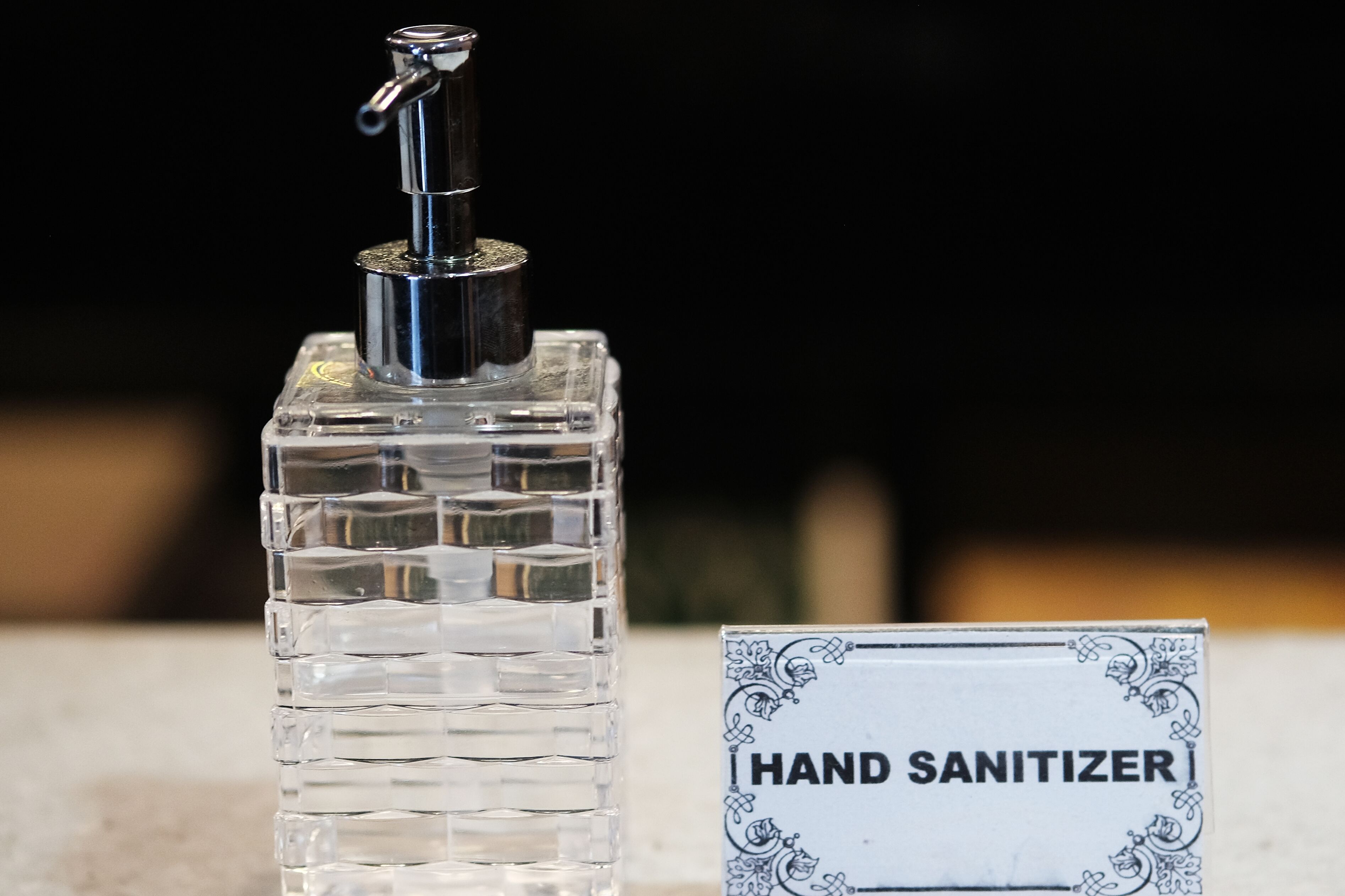 A hand sanitizer bottle with a pump dispenser and a sign labeled "HAND SANITIZER".