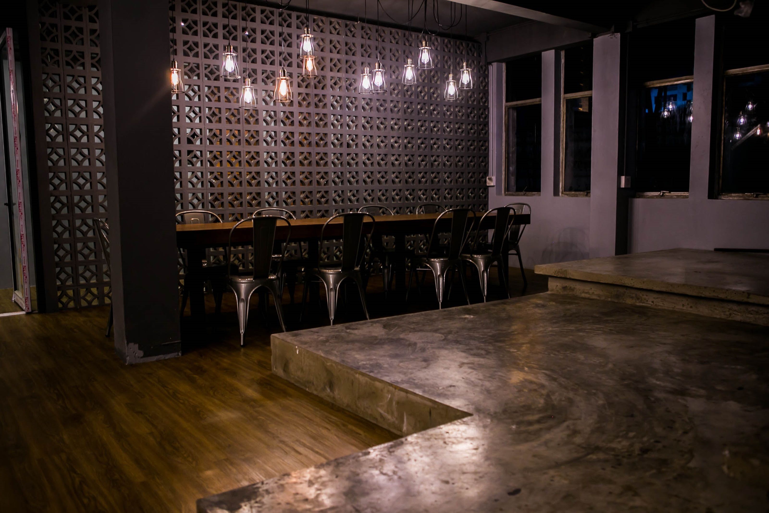 A dining area with a wooden table and chairs, a decorative wall with a lattice pattern, and pendant lighting.