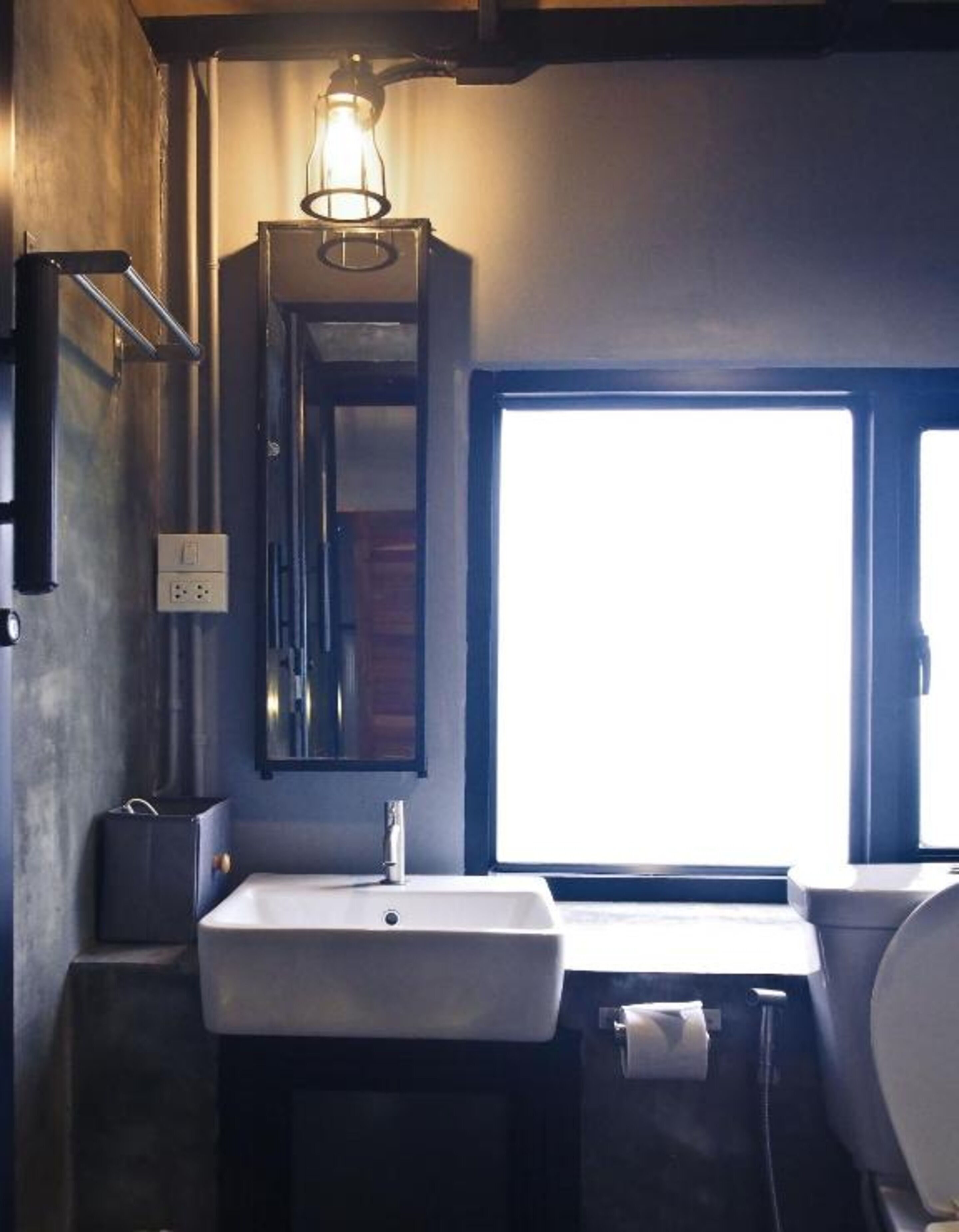 A bathroom with a large window, a sink, and a mirror.