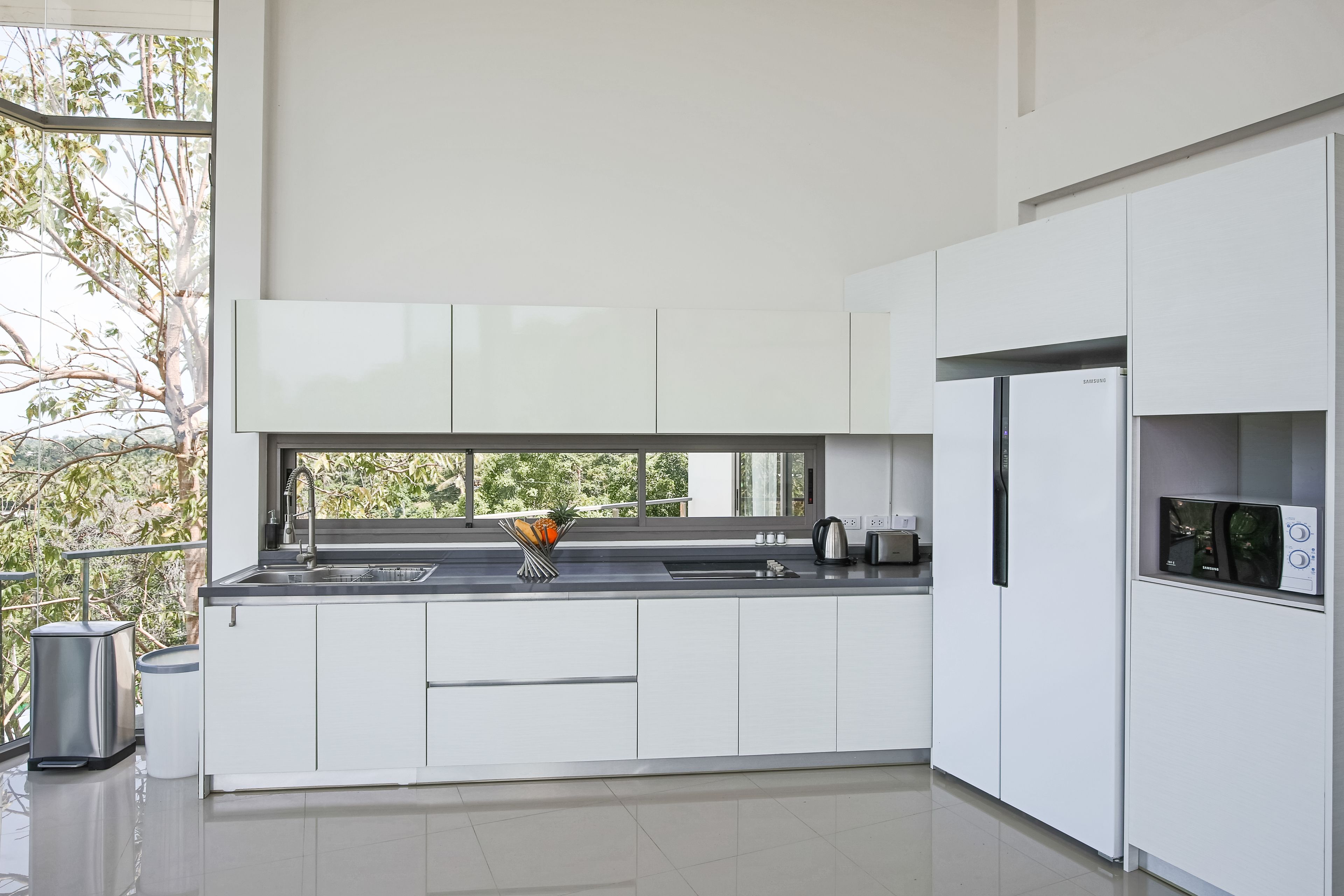 A modern kitchen with white cabinets, a stainless steel sink, and a built-in microwave.
