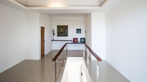 Ein modernes Interieur mit einer Holztür, einer Treppe mit Glasgeländer und Wandbildern.