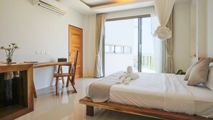 Ein modernes Hotelzimmer mit einem großen Bett, einem Holztisch und Blick ins Freie.