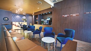 Eine moderne Lobby mit blauen Stühlen, einem Empfangsbereich und einem Brandschutzzimmer.