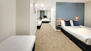 Ein Hotelzimmer mit zwei Einzelbetten, einem Schreibtisch, einem Stuhl und einem kleinen Tisch.