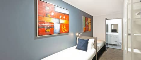 Un cuarto de hotel con cama, mesita de noche, espejo y un cuadro en la pared.