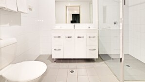 Ein modernes Badezimmer mit Toilette, Waschbecken mit Spiegel darüber und einer Duschkabine.