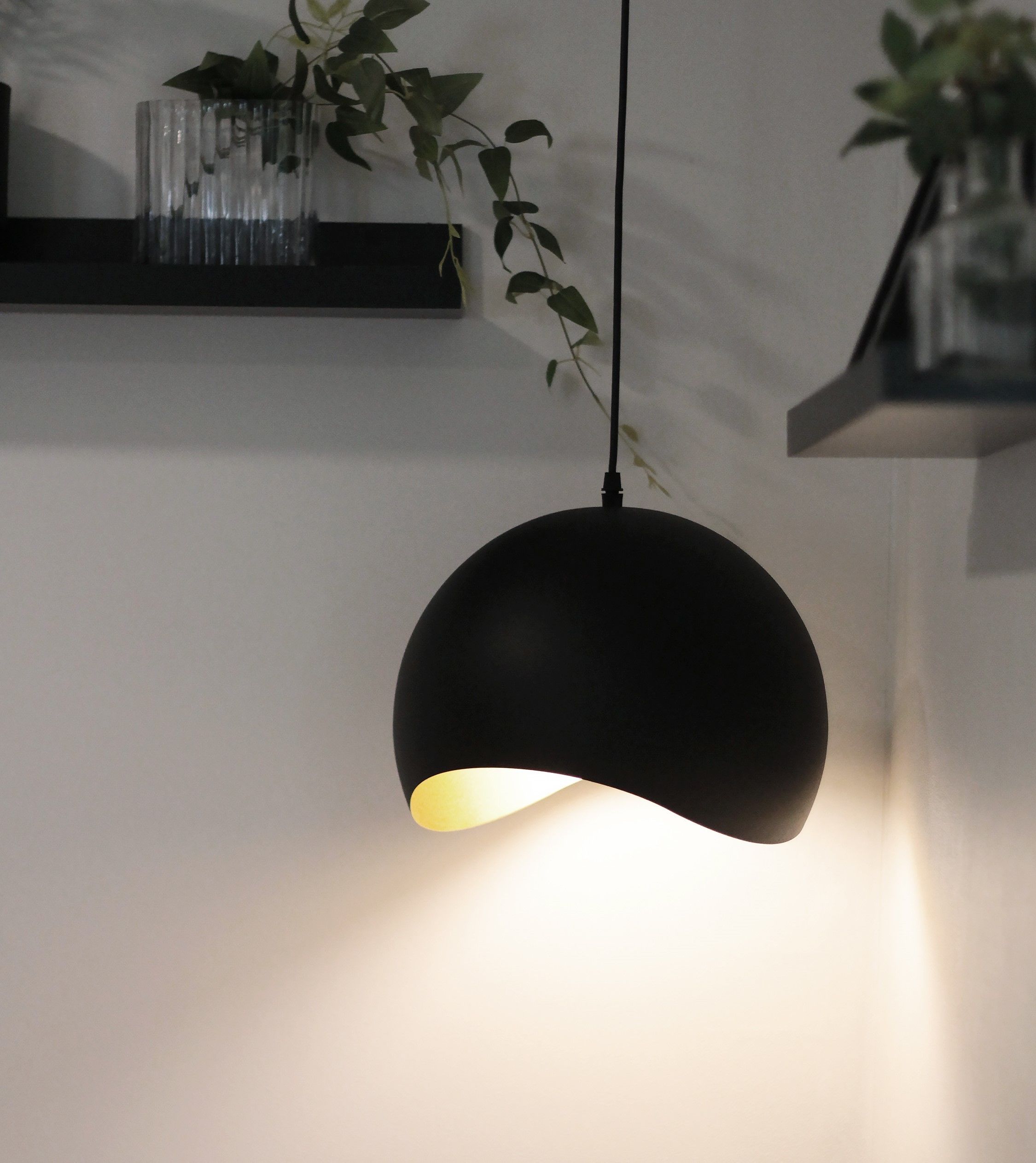 A pendant light fixture with a black shade and a visible light source.