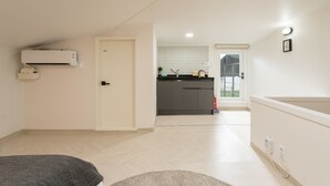 A modern apartment with a kitchenette, a door leading to a balcony, and a visible air conditioning unit. - Neat House (Seoul)
