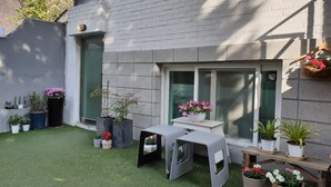 A small patio area with artificial grass, a table, and several potted plants. - Neat House (Seoul)