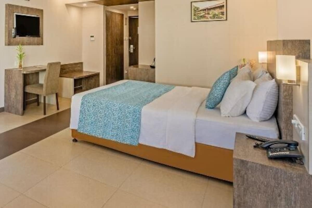 Une chambre d’hôtel équipée d’un lit, d’un bureau, d’une chaise et d’un téléviseur.