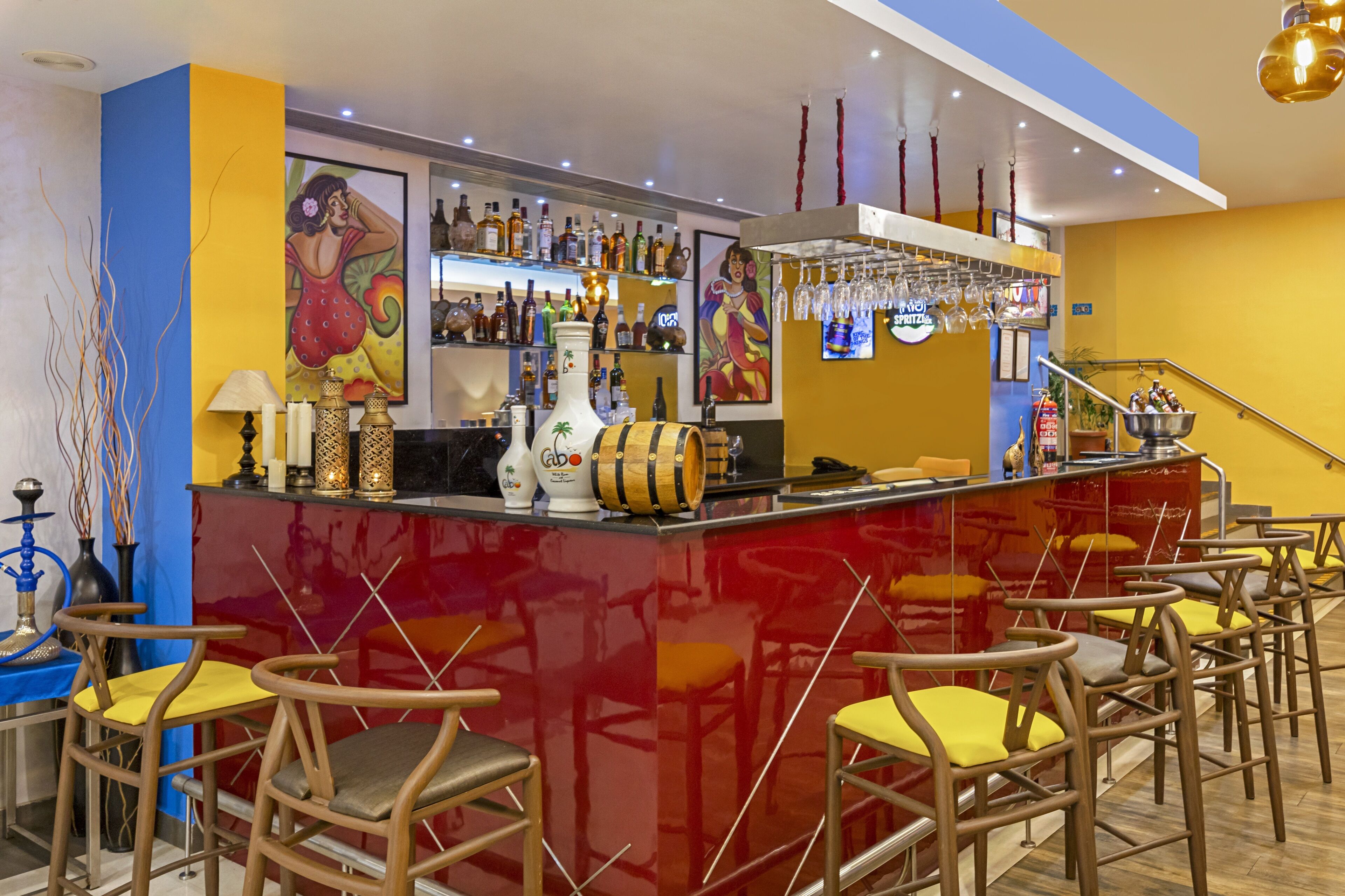 Eine Bar mit roter Bar, verschiedenen Sitzgelegenheiten und einer Auswahl an Flaschen und Gläsern.