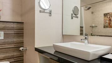 A modern bathroom with a large sink, a mirror, and a shower area.