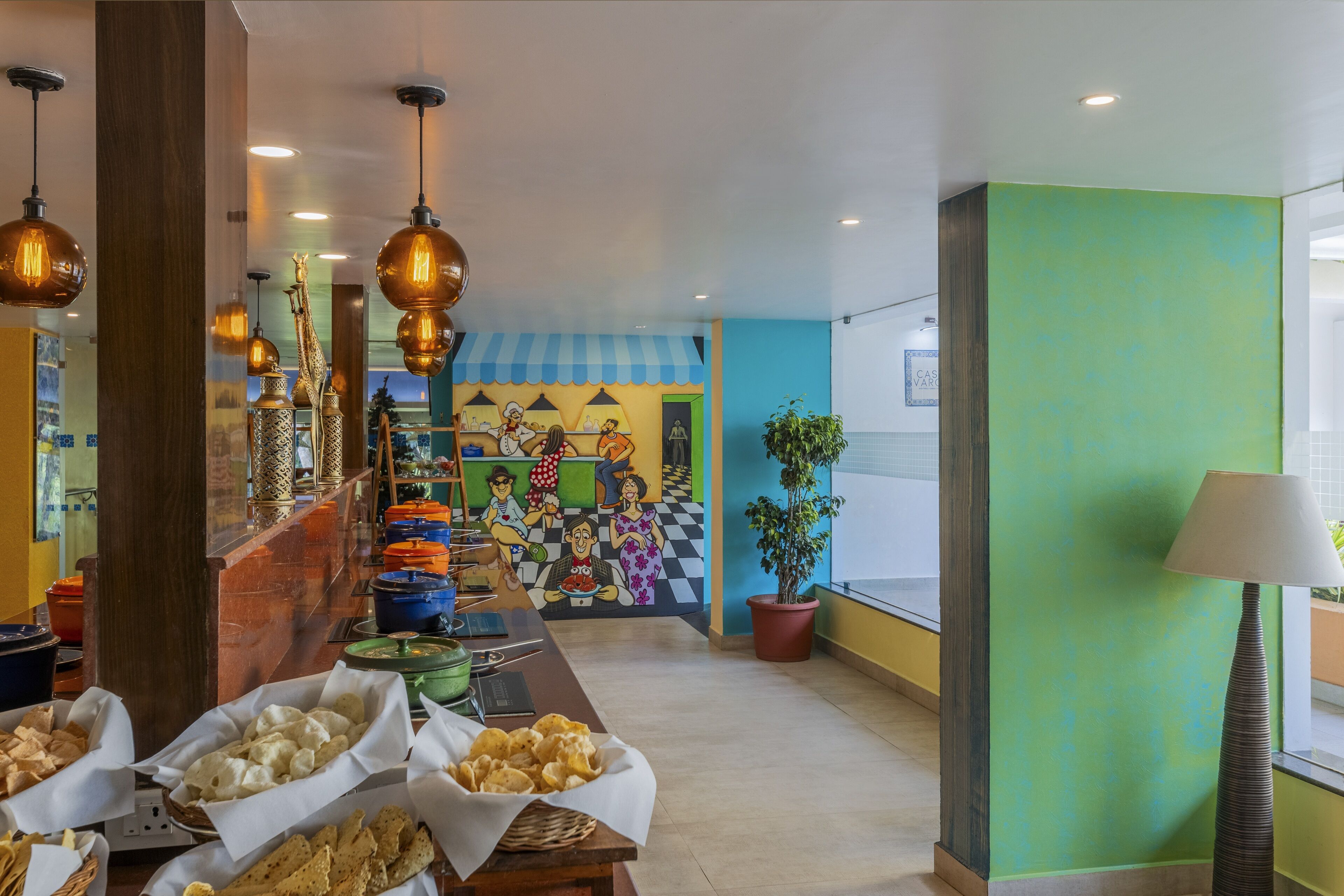 A buffet area with various food items and a colorful mural in the background.