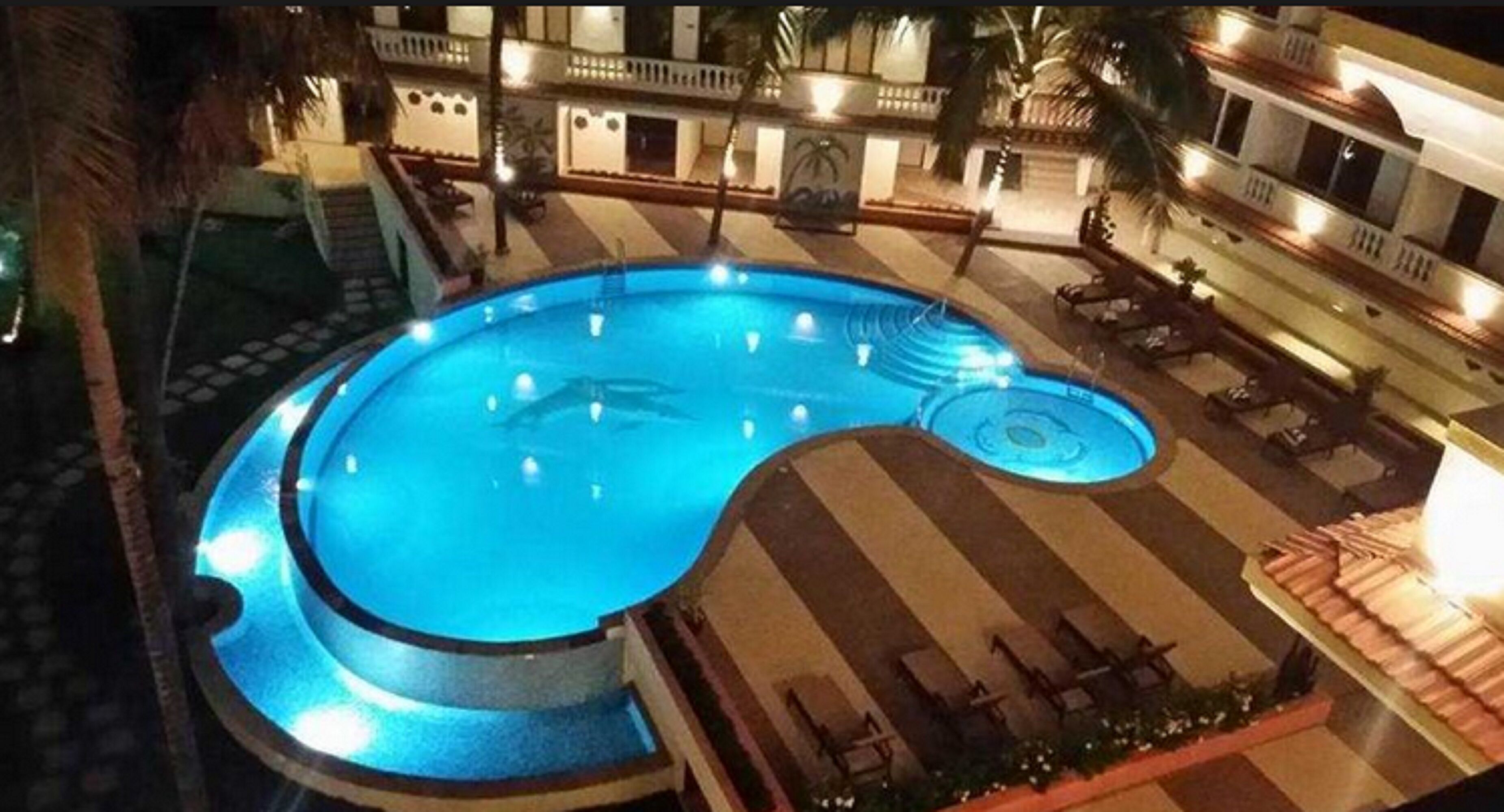 A swimming pool with a circular design, surrounded by a tiled deck and lounge chairs.