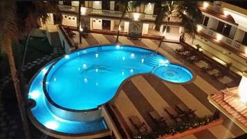 A swimming pool with a circular design, surrounded by a tiled deck and lounge chairs.