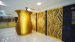 A reception area with a large golden vase, a reception desk, and decorative panels. - five6 Hotel Splendour (Singapore)