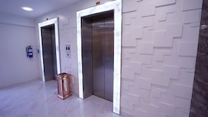 An elevator area with two elevators, a fire extinguisher, and a trash bin. - five6 Hotel Splendour (Singapore)
