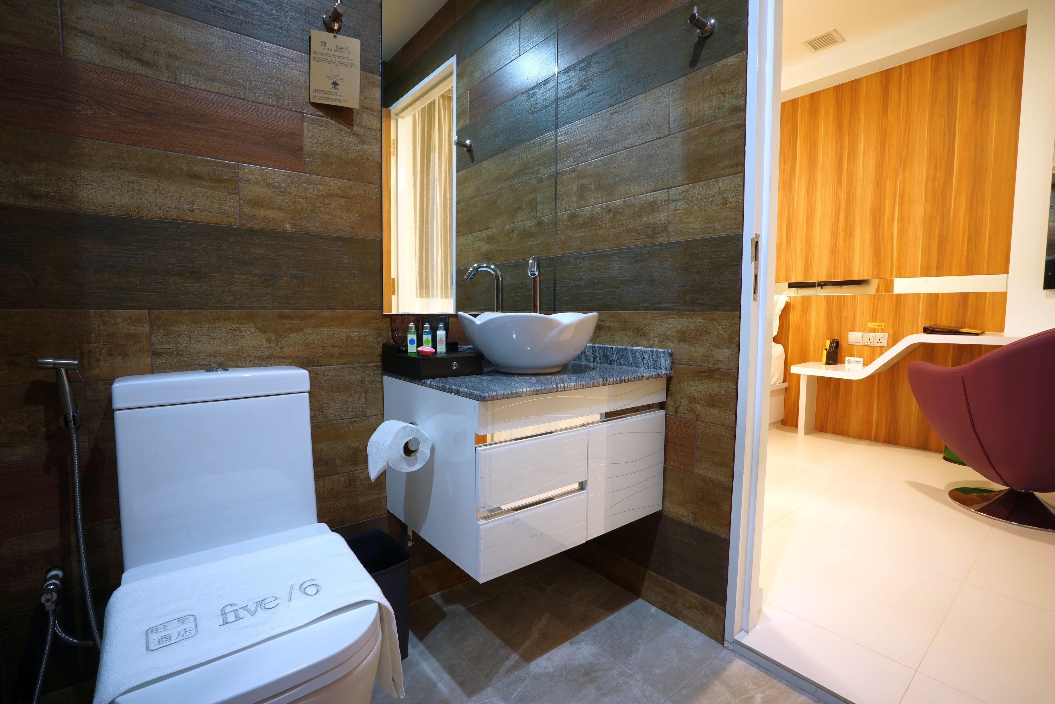 A modern bathroom with a white toilet, a vessel sink, and a wooden vanity.