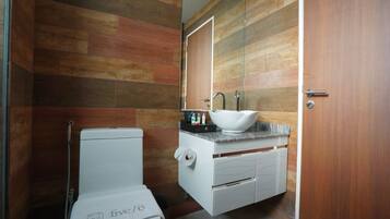 A bathroom with a toilet, a sink with a marble countertop, and a mirror above the sink.