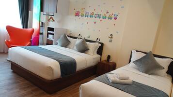 Quarto de hotel com duas camas, piso de madeira, uma cadeira colorida, guarda-roupa e parede decorada com tema de trem.