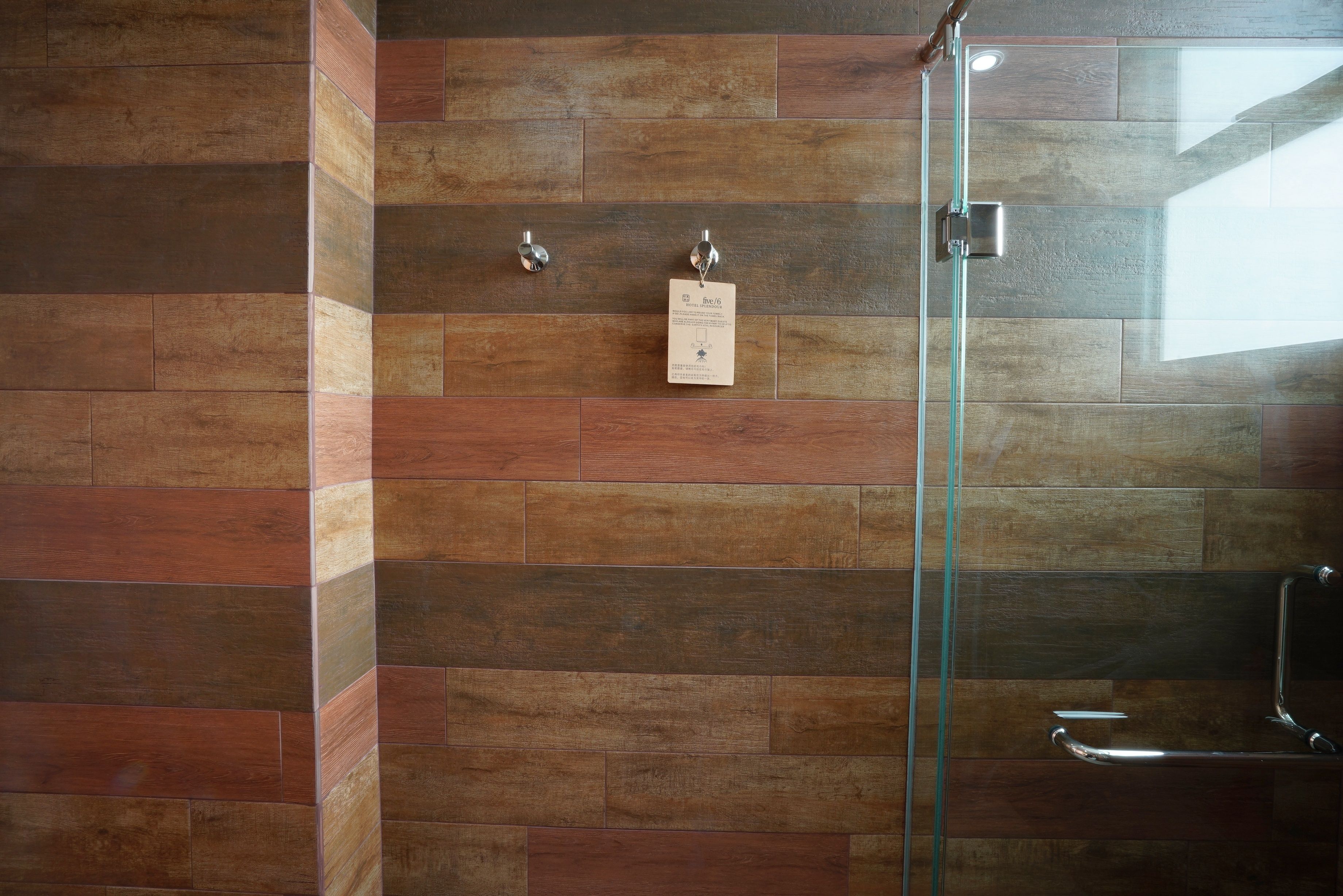 A shower with a glass door, a metal towel rack, and a wall-mounted towel dispenser.