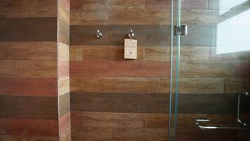 A shower with a glass door, a metal towel rack, and a wall-mounted towel dispenser.
