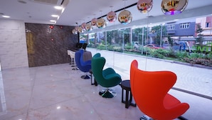 A modern reception area with a marble floor, colorful chairs, and a view of the street outside. - five6 Hotel Splendour (Singapore)