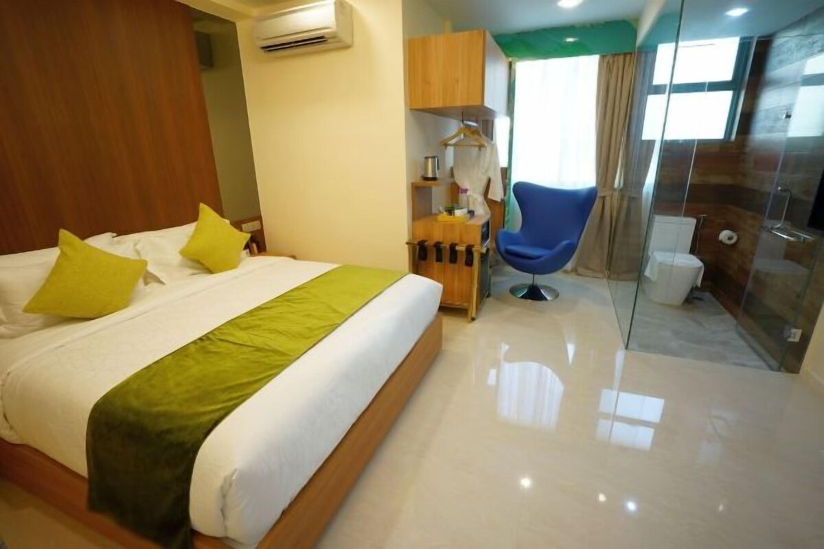 A hotel room with a bed, a small desk, a chair, and a shower area.