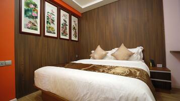 Un dormitorio ordenado con una cama grande, paneles de madera en las paredes y cuadros con motivos florales sobre la cama.