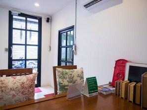 A room with a wooden desk, a red clock, a laptop, and a sign.