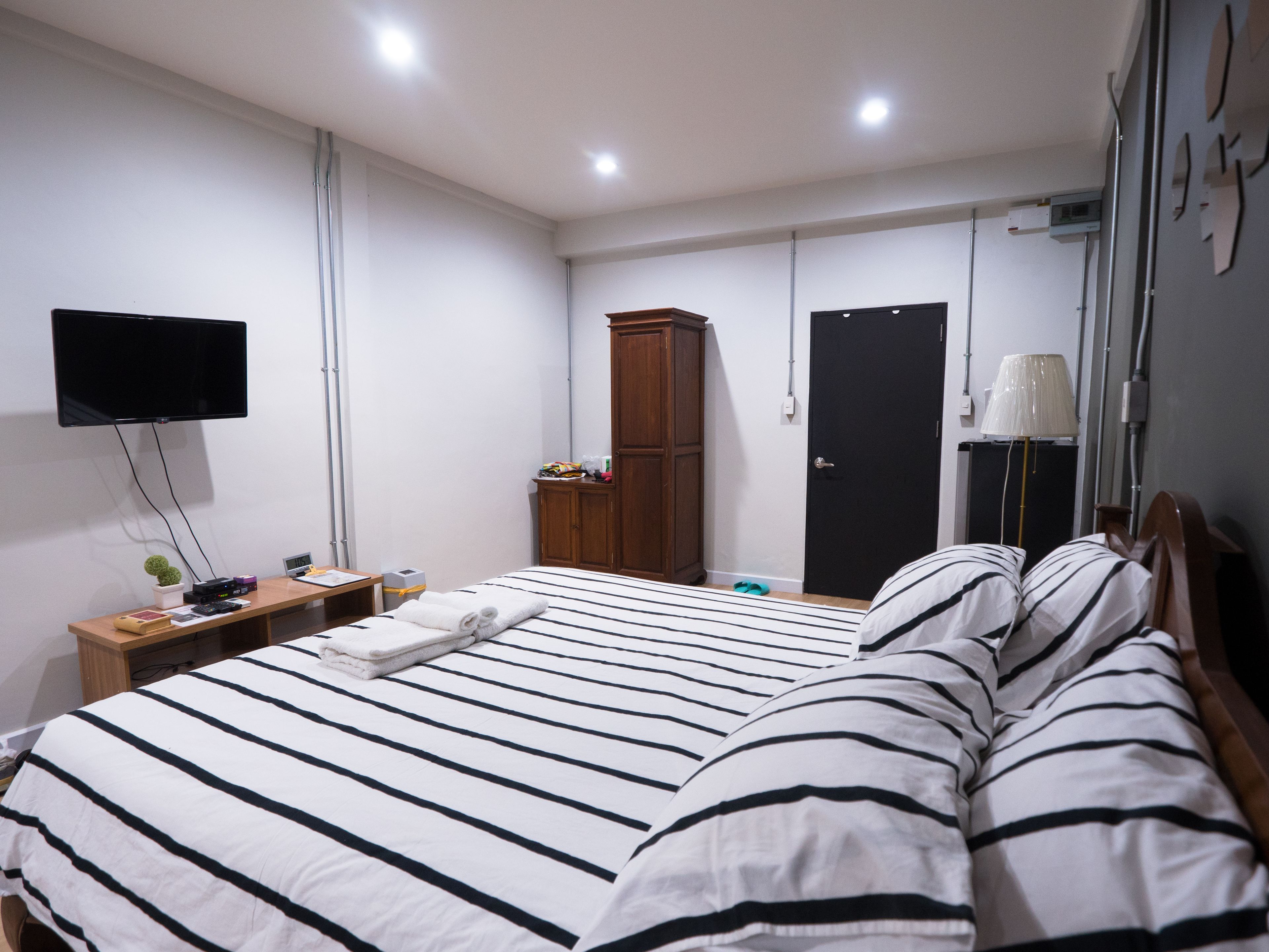 Habitación de hotel con cama, televisor montado en la pared, armario y puerta.