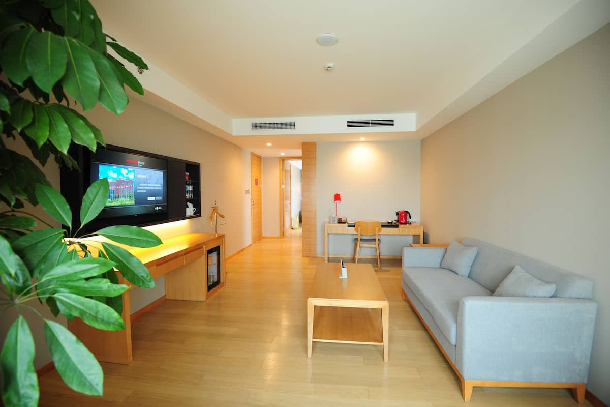 A modern living room with a sofa, a coffee table, a TV, and a dining area.