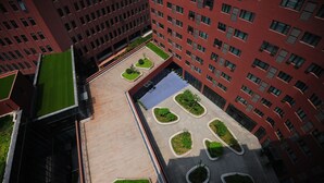 Un edificio di grandi dimensioni con numerosi piani, dotato di un giardino pensile con diverse aree verdi e percorsi.
