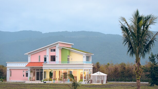 A multi-story house with a flat roof, a balcony, and a small garden area.