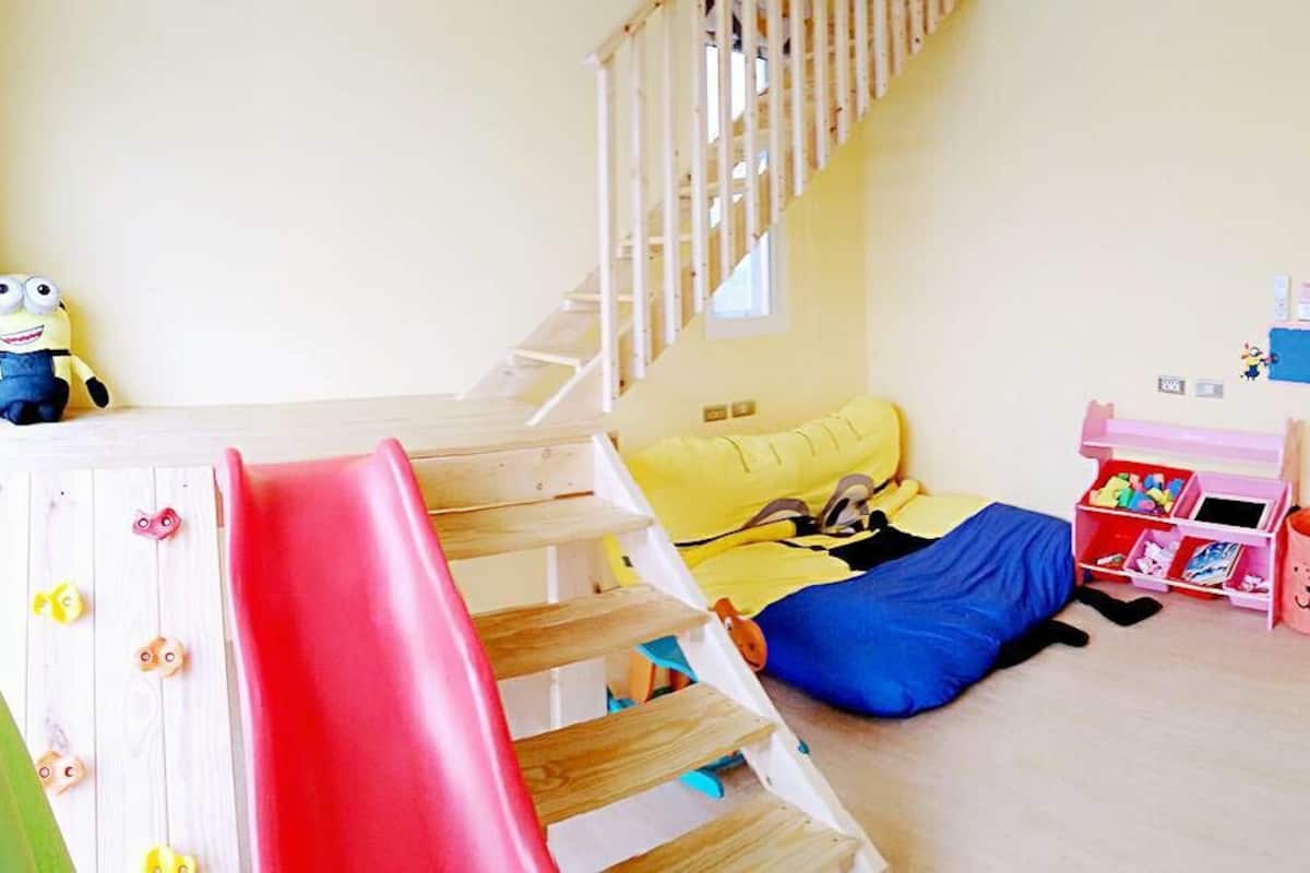 A child's bedroom with a bunk bed, a play area with toys, and a TV.