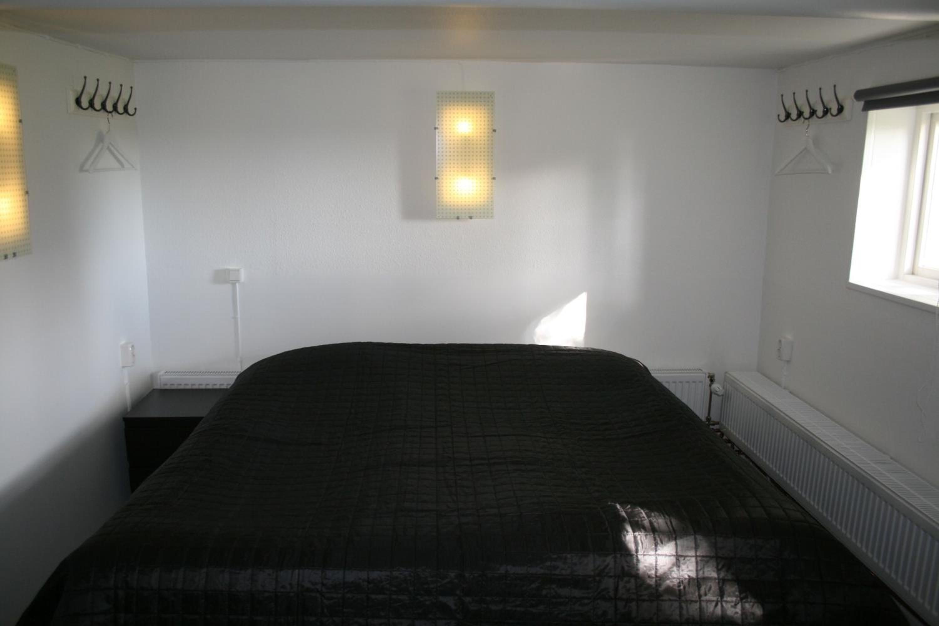 A room with a bed, a window, and wall-mounted lights.